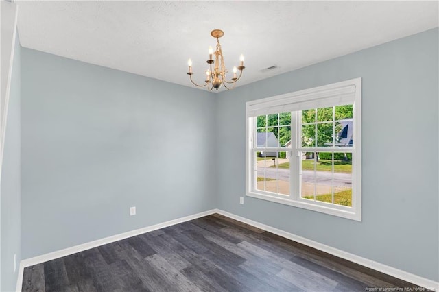 unfurnished room with an inviting chandelier, baseboards, dark wood-style flooring, and visible vents