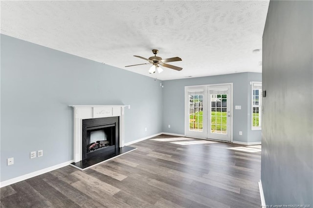 unfurnished living room featuring baseboards, a fireplace with raised hearth, ceiling fan, and wood finished floors