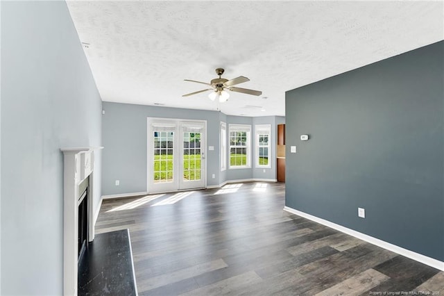 unfurnished living room featuring a ceiling fan, dark wood-style floors, and a textured ceiling