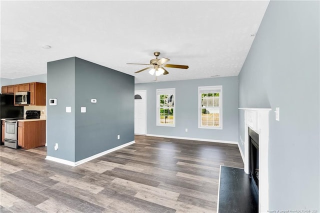 unfurnished living room featuring a fireplace with flush hearth, baseboards, a ceiling fan, and wood finished floors