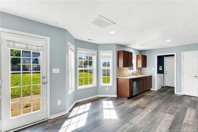 kitchen featuring light countertops, baseboards, dark wood-type flooring, stainless steel dishwasher, and visible vents