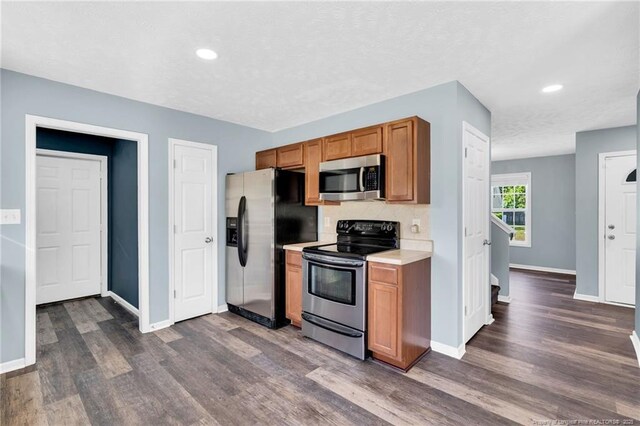 kitchen featuring light countertops, dark wood finished floors, stainless steel appliances, baseboards, and recessed lighting
