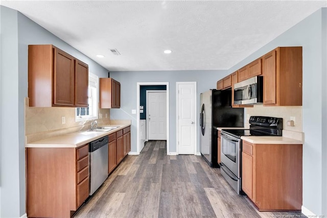 kitchen featuring backsplash, light countertops, appliances with stainless steel finishes, and wood finished floors