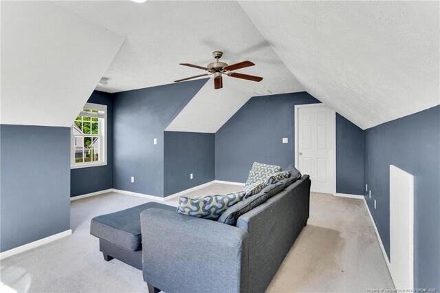 living area with carpet flooring, a ceiling fan, baseboards, and vaulted ceiling