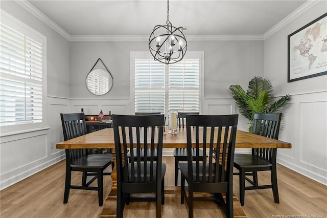 dining space featuring an inviting chandelier, crown molding, a decorative wall, and wood finished floors