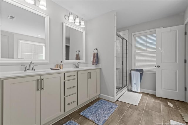 bathroom with visible vents, a shower stall, a sink, and a wealth of natural light
