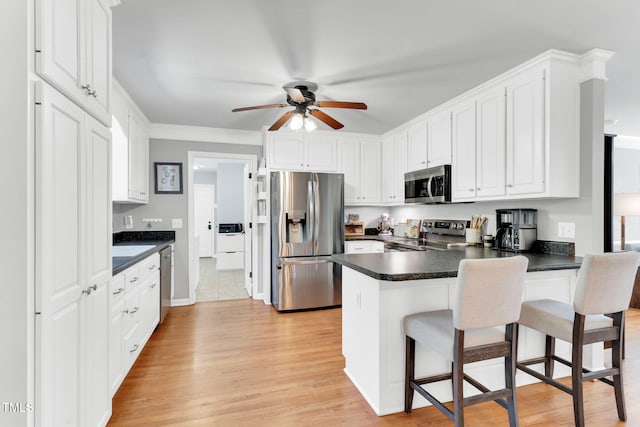 76 Bergeson Ct, Fuquay Varina, NC 27526 - kitchen with appliances with stainless steel finishes, a peninsula, dark countertops, ceiling fan, and white cabinetry