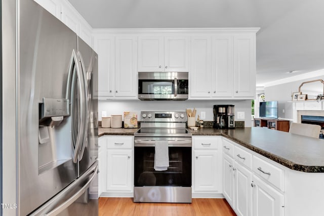 76 Bergeson Ct, Fuquay Varina, NC 27526 - kitchen with appliances with stainless steel finishes, dark countertops, a peninsula, white cabinetry, and ornamental molding