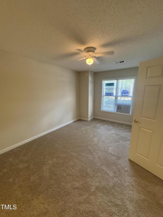 carpeted spare room featuring baseboards, a ceiling fan, a textured ceiling, and visible vents