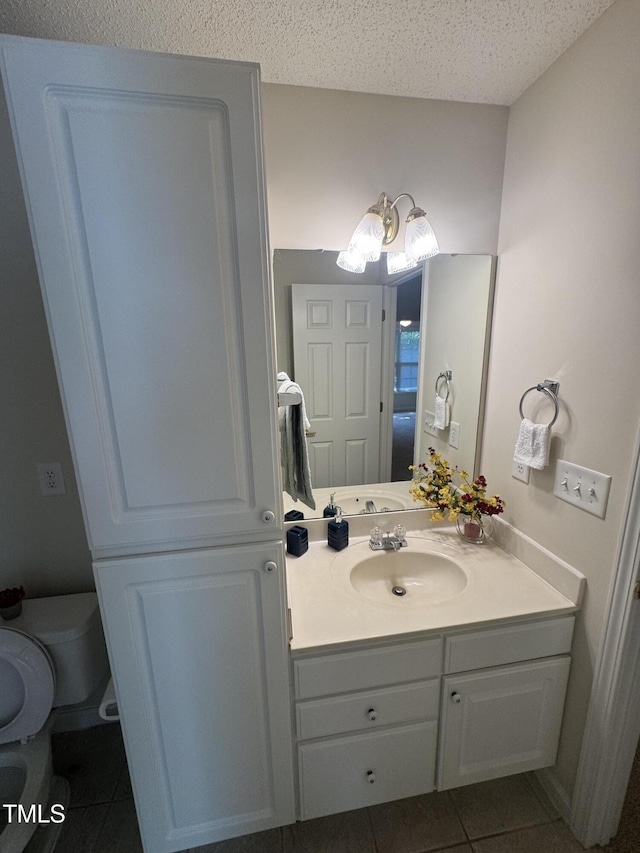 bathroom featuring tile patterned floors, vanity, toilet, and a textured ceiling