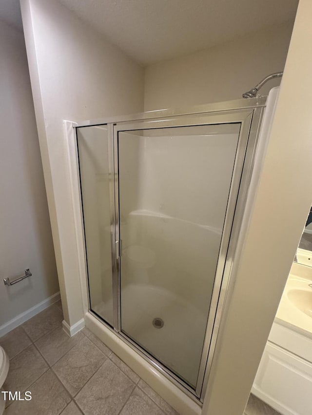bathroom with baseboards, tile patterned floors, toilet, and a shower stall