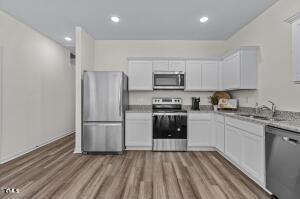 kitchen featuring a sink, appliances with stainless steel finishes, wood finished floors, and white cabinets