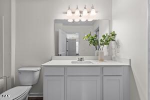 bathroom with toilet, an inviting chandelier, and vanity