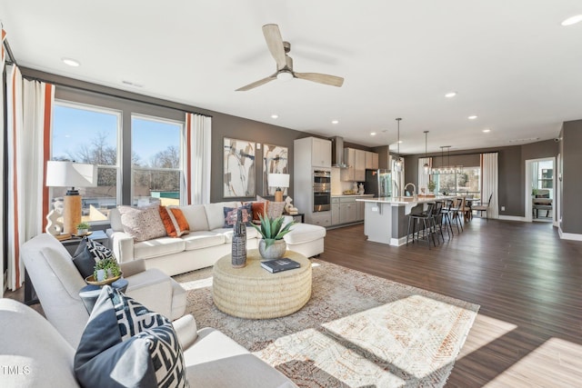 living area with a ceiling fan, visible vents, dark wood finished floors, baseboards, and recessed lighting