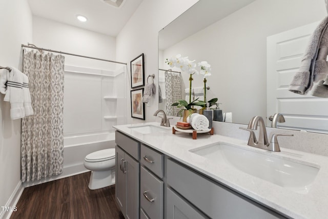 full bath featuring a sink, double vanity, toilet, and wood finished floors