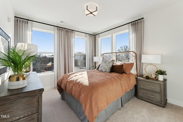 bedroom featuring baseboards, multiple windows, and light colored carpet