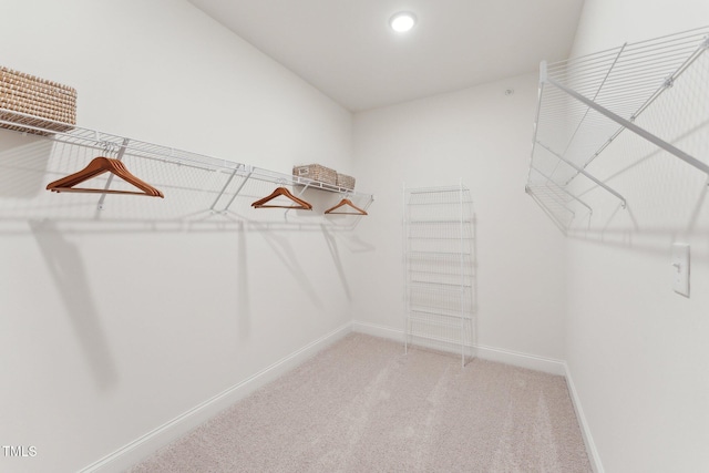 spacious closet with lofted ceiling and light colored carpet