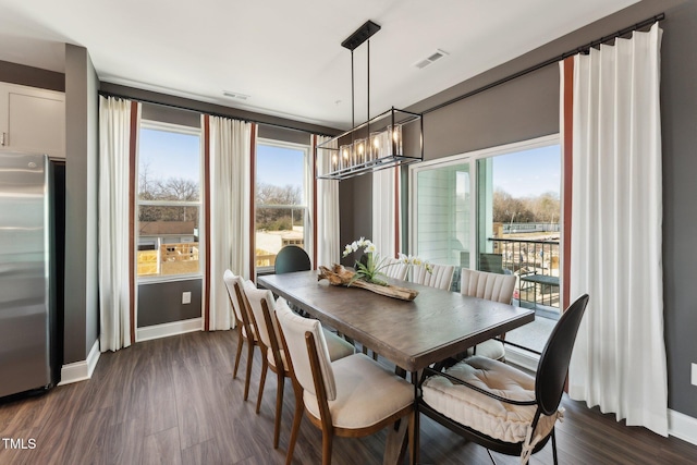 dining area featuring visible vents, dark wood-style flooring, baseboards, and a chandelier