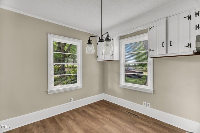 2677 NC-39, Henderson, NC 27537 - unfurnished dining area with crown molding, dark wood-style flooring, a textured ceiling, baseboards, and visible vents