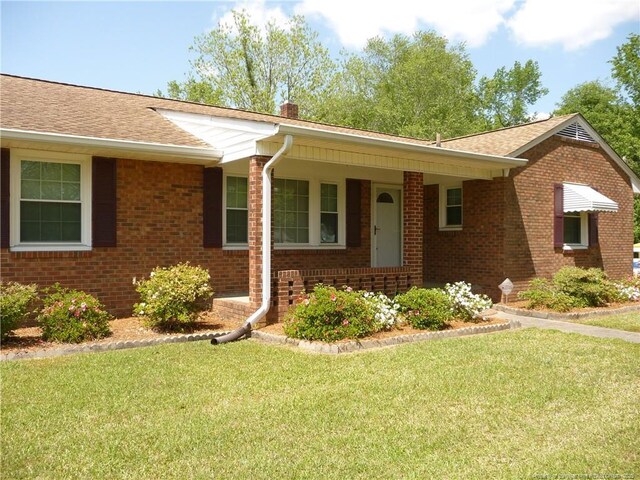185 Meadow Rd, Lumberton, NC 28358 - ranch-style house with roof with shingles, a front lawn, brick siding, a porch, and a chimney