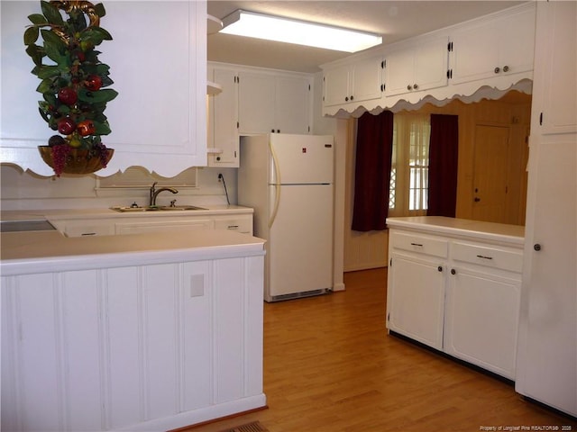185 Meadow Rd, Lumberton, NC 28358 - kitchen featuring white cabinetry, a sink, light countertops, freestanding refrigerator, and light wood-style flooring
