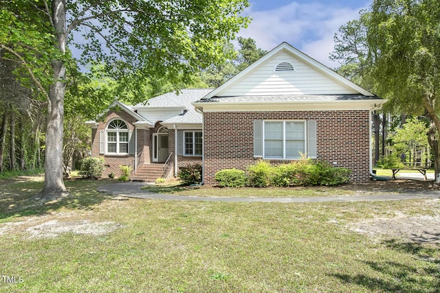 view of front of house featuring brick siding, a shingled roof, and a front yard