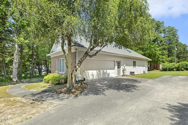 view of side of home with a garage, a yard, and concrete driveway