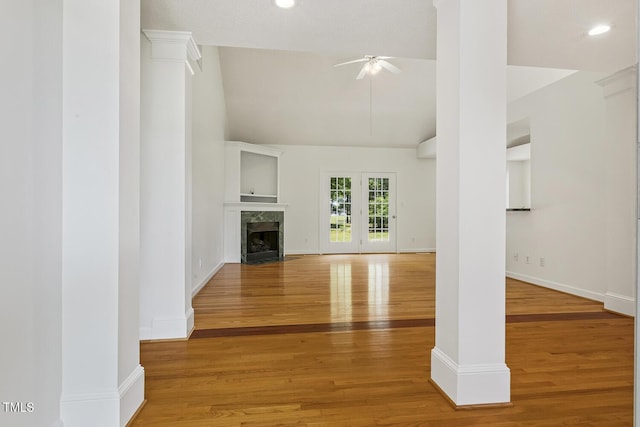unfurnished living room with ceiling fan, a fireplace, wood finished floors, baseboards, and lofted ceiling