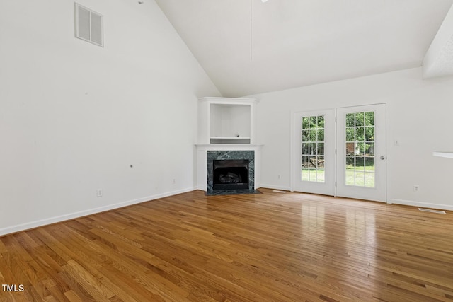 unfurnished living room with visible vents, wood finished floors, and a high end fireplace