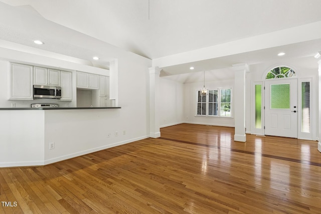 unfurnished living room with ornate columns, baseboards, recessed lighting, and hardwood / wood-style floors