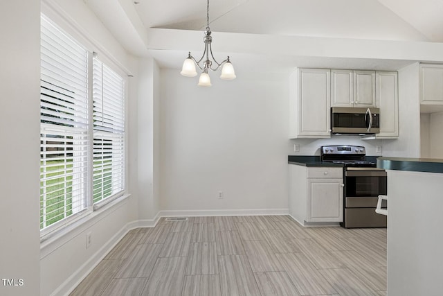 kitchen featuring baseboards, appliances with stainless steel finishes, a wealth of natural light, and an inviting chandelier