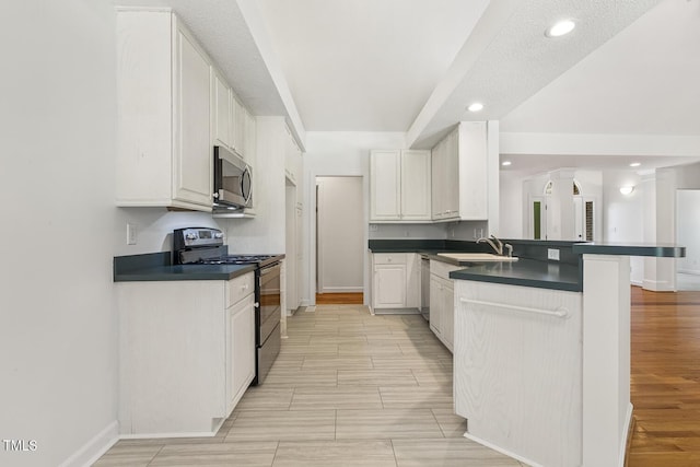 kitchen featuring dark countertops, appliances with stainless steel finishes, wood tiled floor, and a peninsula