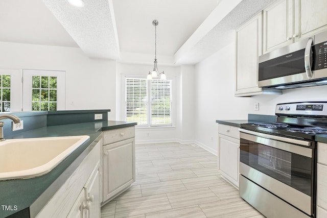 kitchen featuring hanging light fixtures, dark countertops, appliances with stainless steel finishes, and a sink