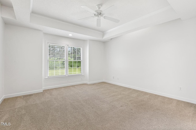 empty room featuring crown molding, carpet flooring, ceiling fan, and a raised ceiling