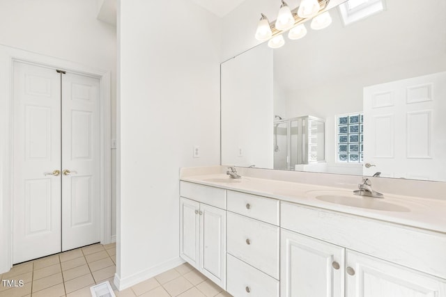 full bathroom with double vanity, tile patterned floors, a shower stall, and a sink