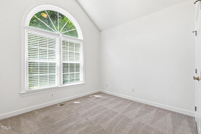 carpeted spare room featuring baseboards, lofted ceiling, and visible vents