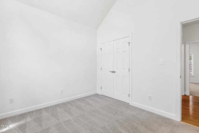 unfurnished bedroom with a closet, baseboards, carpet flooring, and high vaulted ceiling