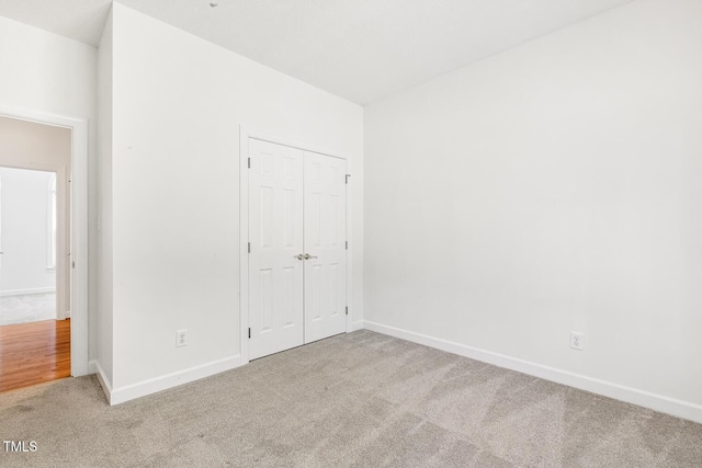 unfurnished bedroom with carpet floors, baseboards, and a closet