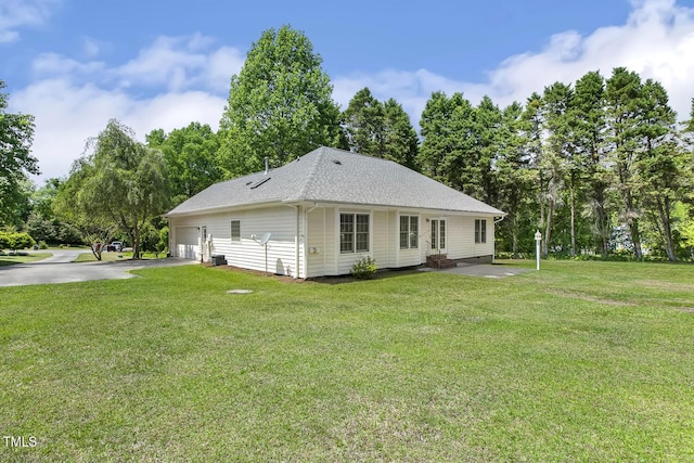 rear view of house featuring a lawn, entry steps, roof with shingles, and a garage