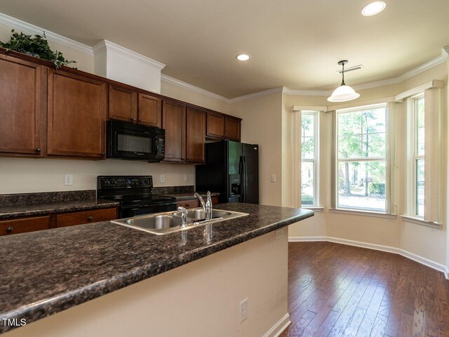 kitchen featuring black appliances, healthy amount of natural light, dark wood finished floors, baseboards, and ornamental molding