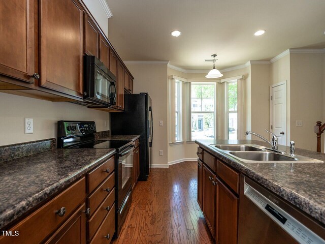 kitchen featuring black appliances, a sink, dark wood-style flooring, dark countertops, and crown molding