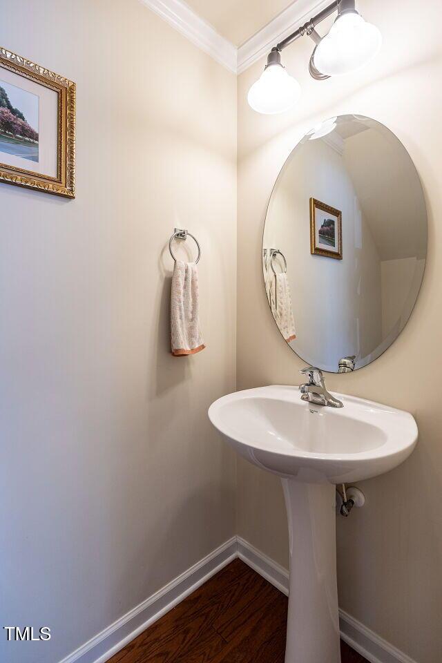 bathroom with crown molding, baseboards, and wood finished floors