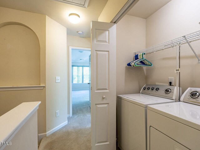 laundry room featuring washing machine and clothes dryer, light colored carpet, and baseboards