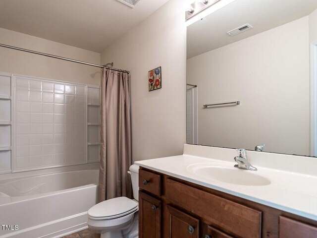 bathroom featuring toilet, shower / bath combo with shower curtain, and vanity