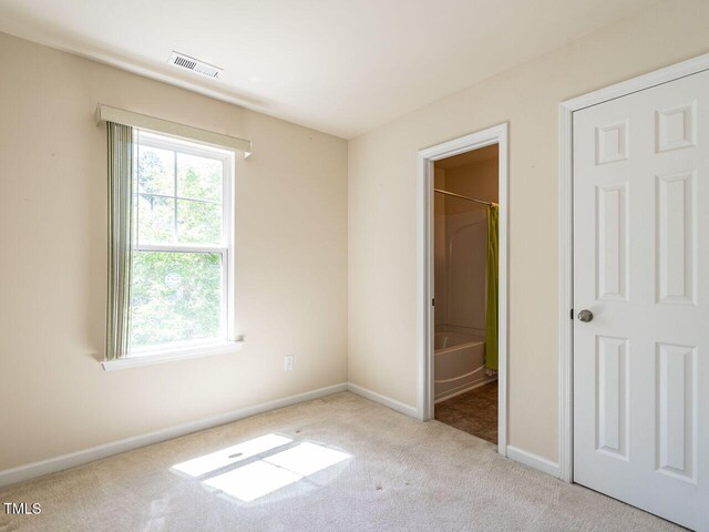 unfurnished bedroom with carpet, baseboards, and ensuite bathroom