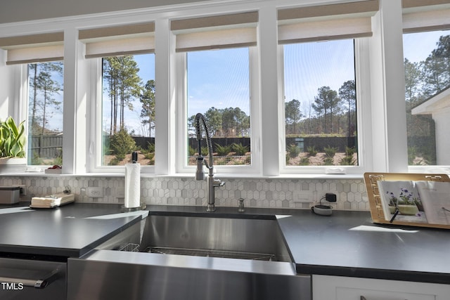 details featuring white cabinetry, dark countertops, a sink, and tasteful backsplash