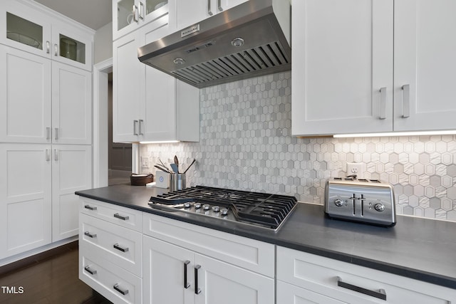 kitchen featuring exhaust hood, dark countertops, stainless steel gas cooktop, and white cabinets