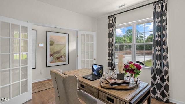 home office featuring baseboards, wood finished floors, visible vents, and beverage cooler