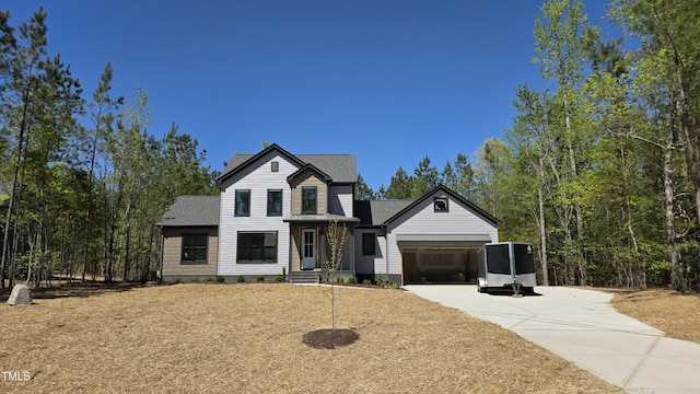 view of front of home featuring roof with shingles, an attached garage, and driveway