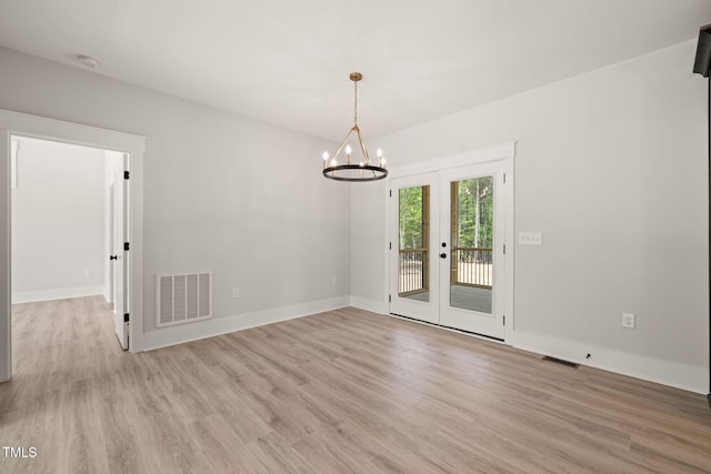 spare room with visible vents, an inviting chandelier, baseboards, french doors, and light wood finished floors